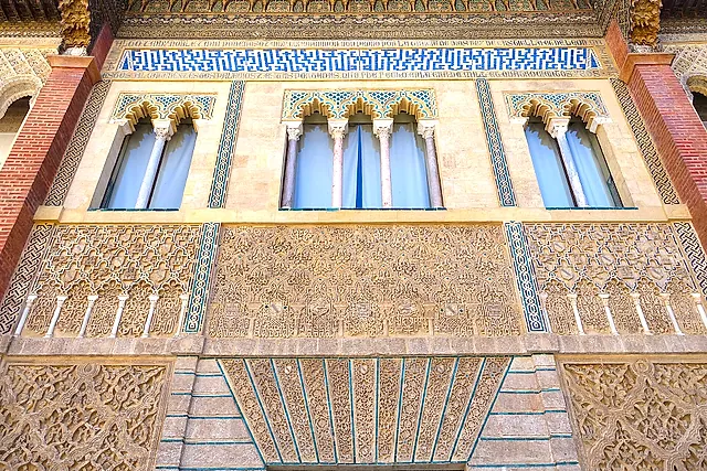 Detail of the facade of Pedro I's palace: ajimez windows, carved stucco panels and a tile band