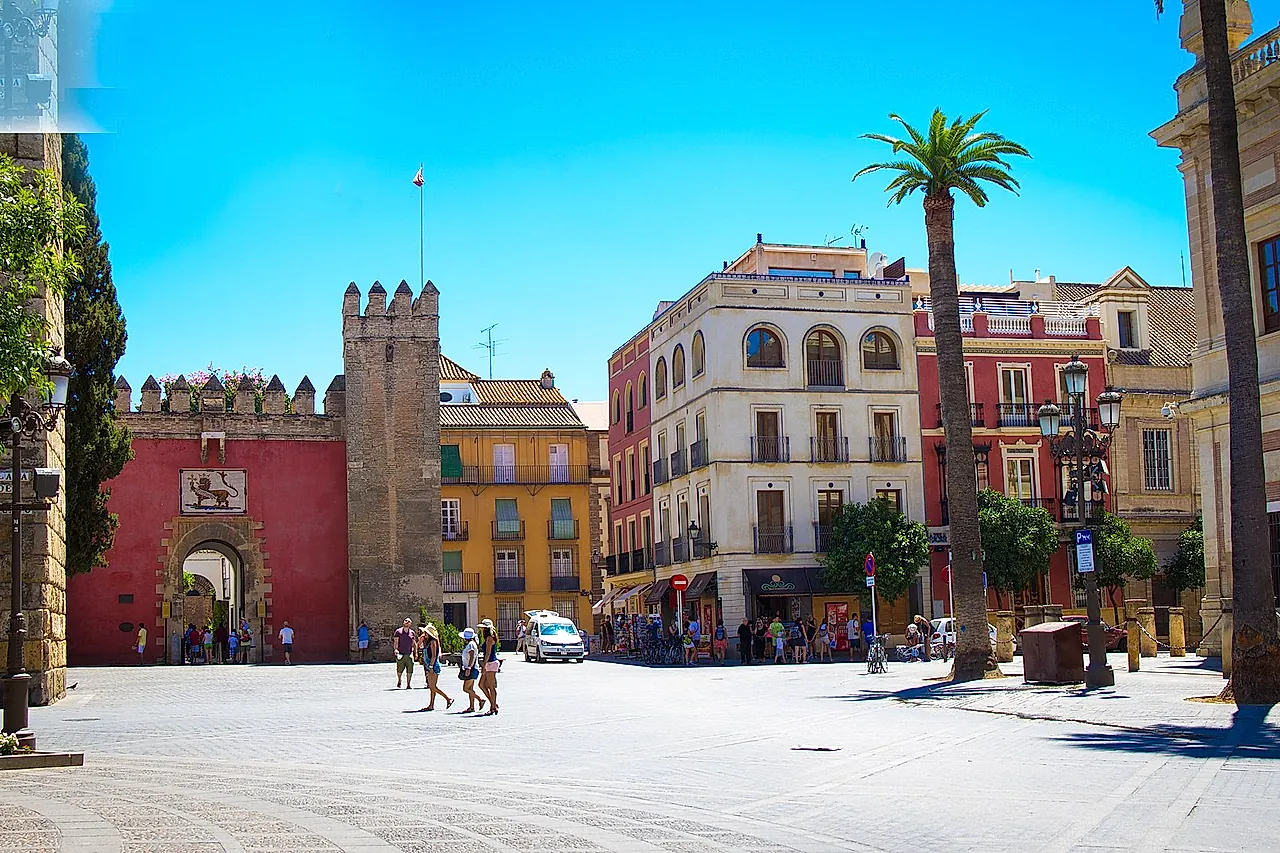 The Puerta del León and its crenellated tower on Plaza del Triunfo, under a blue sky