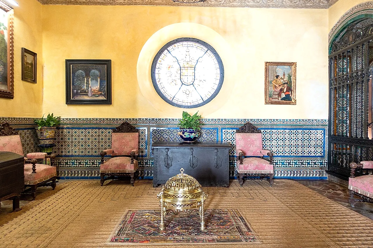 A room with an azulejo dado and a round stained-glass window in the Palacio de las Dueñas