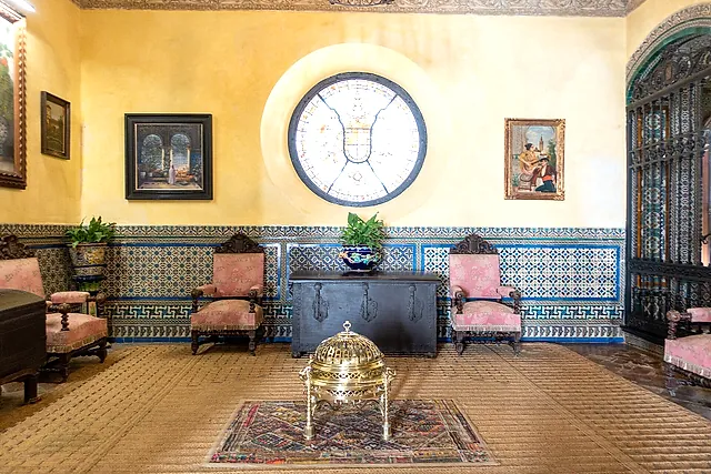 A room with an azulejo dado and a round stained-glass window in the Palacio de las Dueñas
