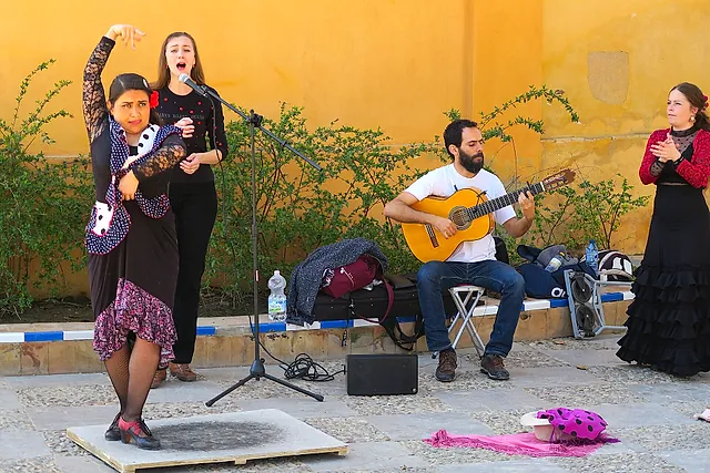 Flamenco dancers, a singer and a guitarist in a courtyard